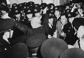 House of Representatives Speaker TSUTSUMI heading for chamber floor while being guarded by police officers. From "Me de Miru Gikaiseiji Hyakunenshi"